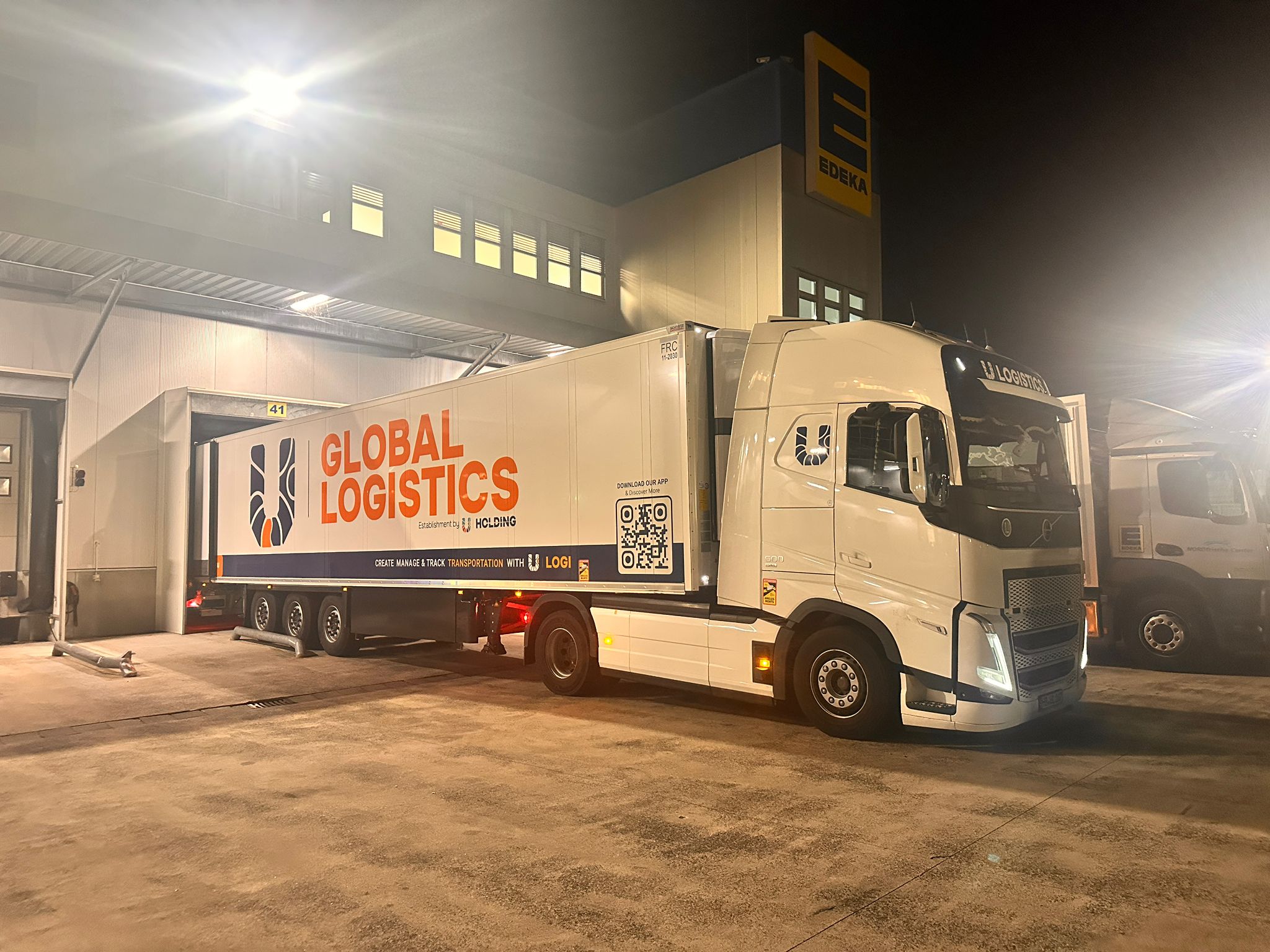 Sattelzug beim Be- und Entladen an einem Logistikzentrum bei Nacht