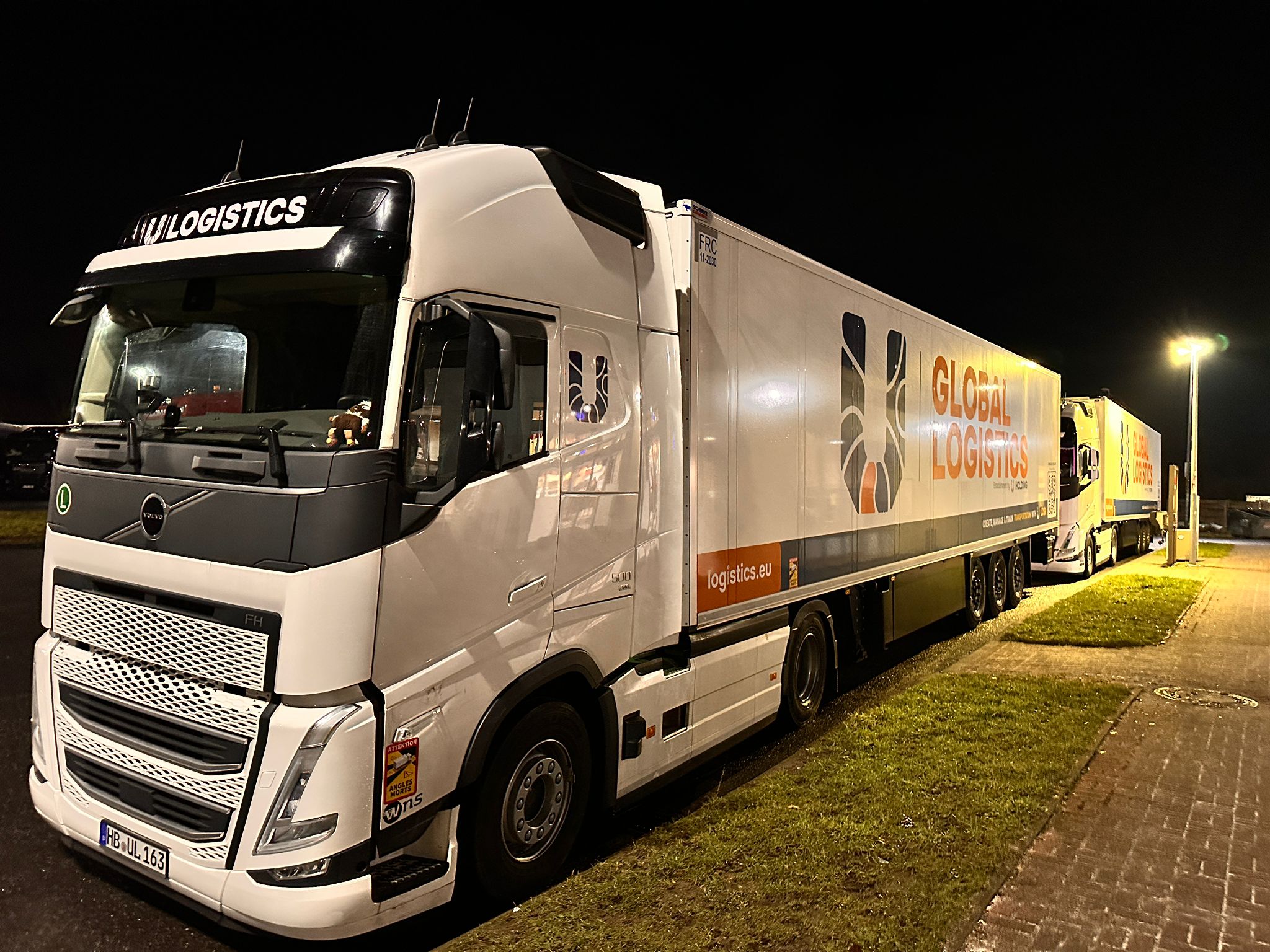 Sattelzüge mit Global-Logistics-Branding bei Nacht